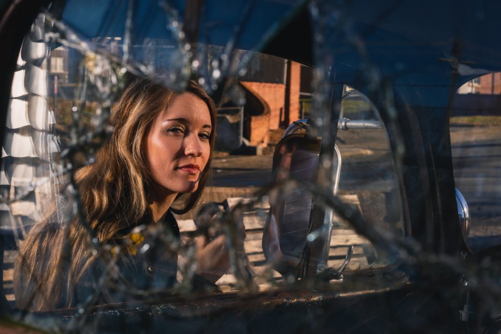 image of a woman looking through a broken car window