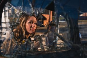 image of a woman looking through a broken car window